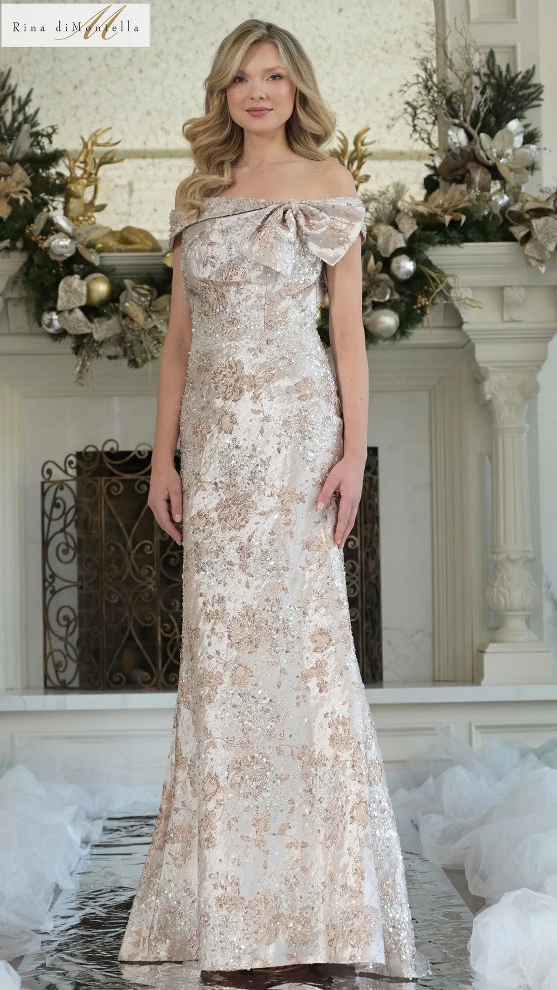 A woman in the Long Formal Dress: Rina Di Montella RD3106, Gold Multi, stands gracefully; its beaded jacquard brocade and mermaid silhouette highlight her elegant presence.